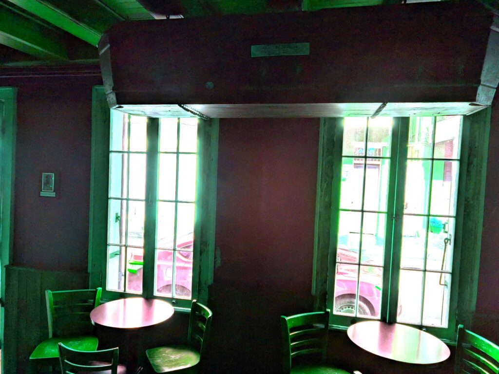 Casket fixed to the ceiling of a bar in front of windows. Suggesting a haunted business in the French Quarter.